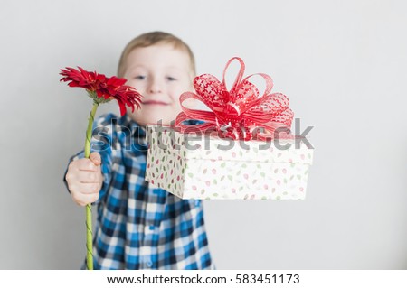 Happy cheerful little boy with red flower and gift box