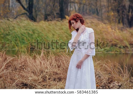 Young happy woman in a park near the river in autumn season