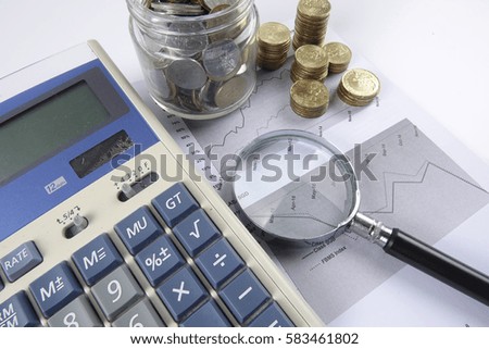 Magnify glass and coins on keyboard. Business analysis concept.