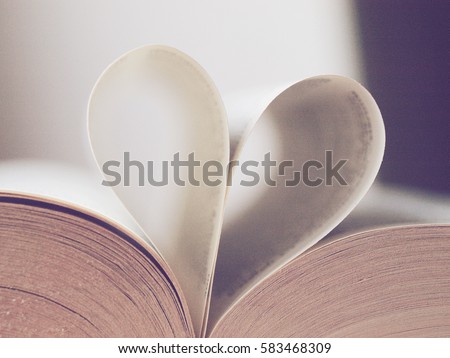 Old open book with pages in heart shape in daylight