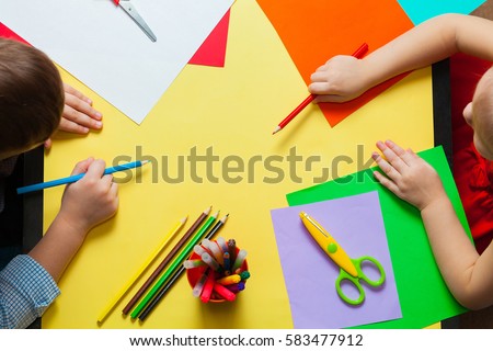Little boy and girl doing crafts. Children ready to draw on colored paper. Top view. 