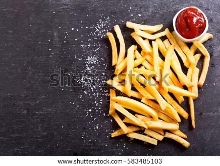 French fries with ketchup on dark table, top view Royalty-Free Stock Photo #583485103