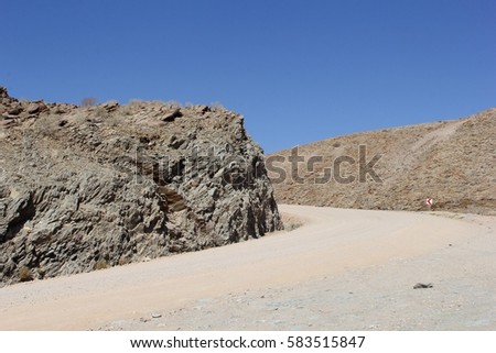 Empty African gravel road between rock walls, rough terrain and offroad in Namibia