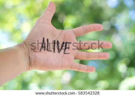 Concept Photo Of A Handwriting Word "ALIVE" On The Left Hand With Blurry Background