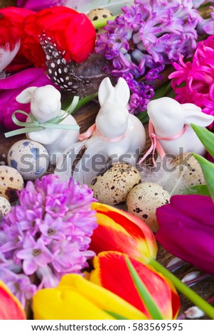 Spring fresh flowers with easter eggs and three white pocelane rabbits