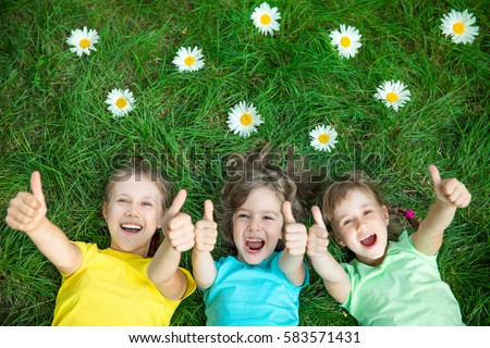 Group of happy children playing outdoors. Kids having fun in spring park. Friends lying on green grass. Top view portrait Royalty-Free Stock Photo #583571431