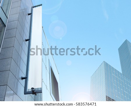 Blank white vertical banner on building facade, design mockup. Store flag mock up on the street. Outdoor banneret template on the side of the shop exterior. Sign hanging on the wall.