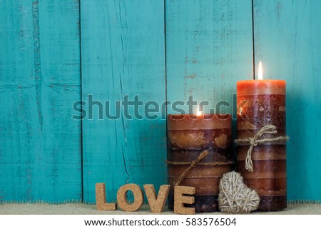 Valentine's Day spa composition with textured candles, rope heart and the word LOVE by antique rustic teal blue wood background;  Mothers Day and love concept background with painted copy space