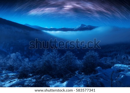 Star trails in a night sky above carpathian winter mountains. Ukraine, Europe.