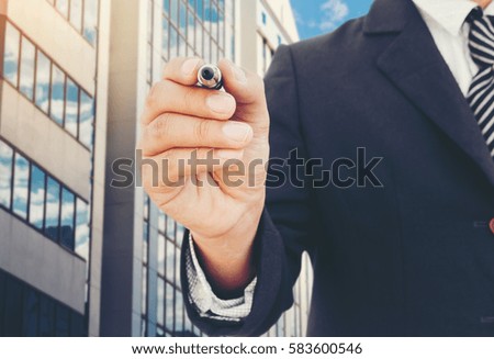 Businessman writing on copy space on Office buildings background