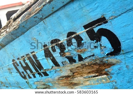 Peeling painted lettering of a dilapidated old fishing vessel