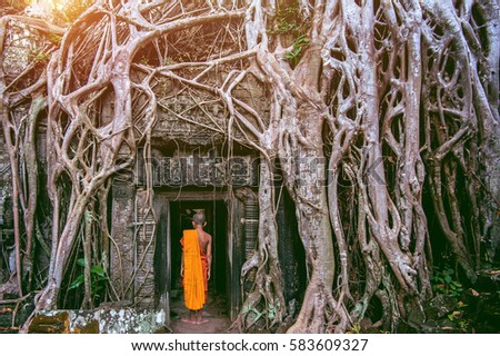 The monks and Trees growing out of Ta Prohm temple, Angkor Wat in Cambodia. Royalty-Free Stock Photo #583609327