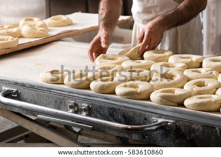 Close-up male baker hands making Italian frisella bread donuts, placing raw dough over bakery table Royalty-Free Stock Photo #583610860