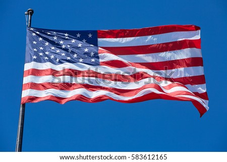 American or USA flag in wind on clear blue sky