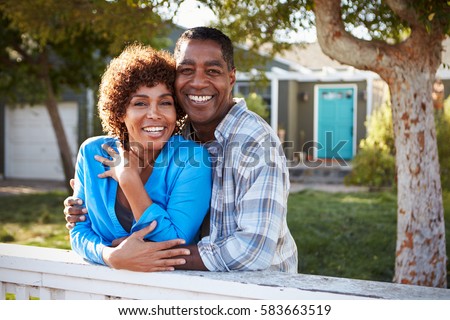 Portrait Of Mature Couple Looking Over Back Yard Fence Royalty-Free Stock Photo #583663519