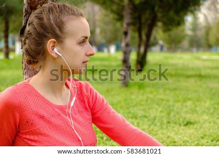 Young girl in headphones listening music in the park