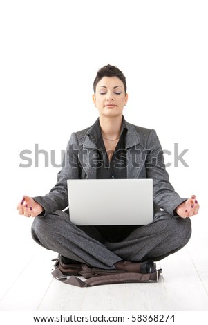 Young businesswoman sitting in yoga lotus position, holding laptop computer, meditating with closed eyes, isolated.