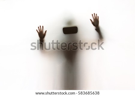 A woman using a Virtual Reality headset behind a white sheet. She's looking for a scape.