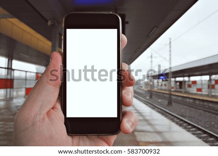 Hand holding smartphone with subway station background