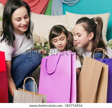 Emotions happiness mother and little cute daughter look in the colored bags near sofa after fun family shopping. 