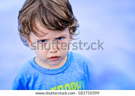 Portrait of toddler boy with angry upset face expression Royalty-Free Stock Photo #583750399