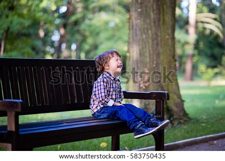 Upset little baby boy crying outdoors. Toddler having tantrum in the park Royalty-Free Stock Photo #583750435