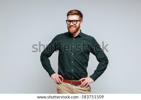 Smiling Bearded man in shirt and eyeglasses which posing with arms at hip Royalty-Free Stock Photo #583751509