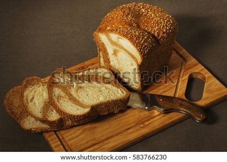 Marble bread loaf and three slices on the old cutting board