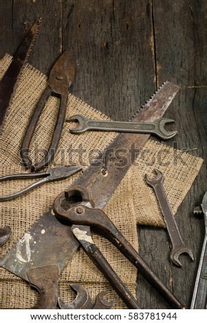 Many old rusty tools scattered on the wooden tstolu. View from above. Space for text.