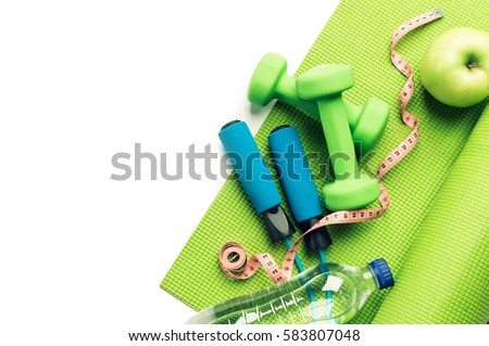 Fitness concept - yoga mat, apple, dumbbells and skipping rope on the white background Royalty-Free Stock Photo #583807048