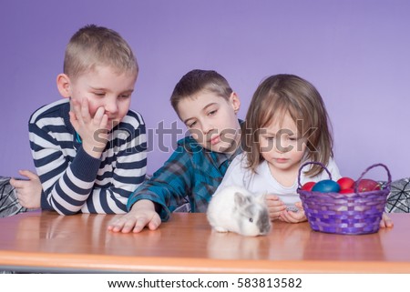 Cheerful kids looking at Easter bunny next to egg basket