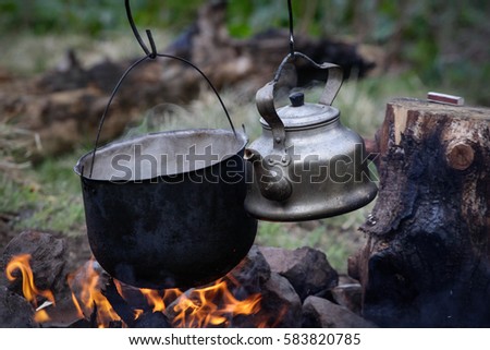 Pot water ant tea pot on the fire, tourists kettle on hot campfire. Camping photo.