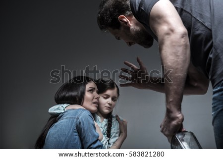 Crying young woman hugging her daughter Royalty-Free Stock Photo #583821280