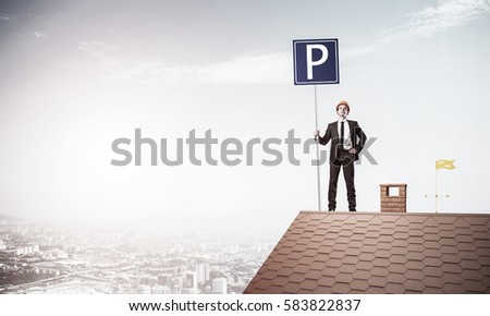 Businessman on house top holding car parking board and viewing city. Mixed media