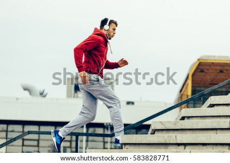 Handsome man running up at stairs Royalty-Free Stock Photo #583828771