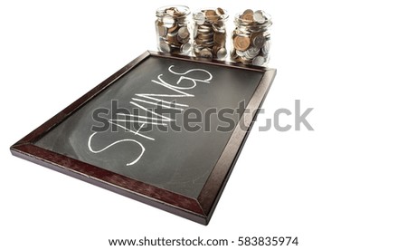 Conceptual images of financial savings, coins in jar with text written on black board.