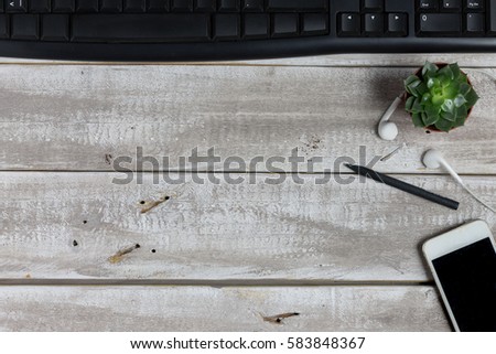 Aerial view of a workspace. Rustic wooden background. Smart Phone, pencil, earphones, cactus flower. Copy space available.