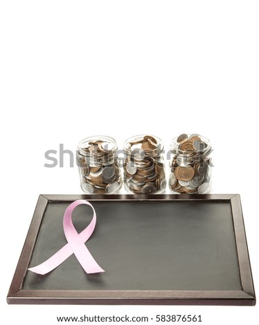 Concept image of breast cancer awareness pink ribbon on a blackboard with coins in mason jar over white background