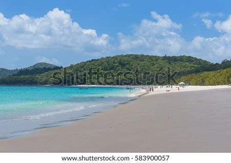 Tropical island beach with people in the distance. Summer vacation background. Tropical paradise getaway scene