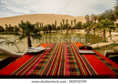 Table prepared with the colors of Peru in front of the small lake in the oasis of Huacachina - Ica - Peru
