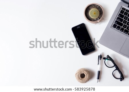 White office desk table with laptop, smartphone, rope, and cactus. Top view with copy space, flat lay.