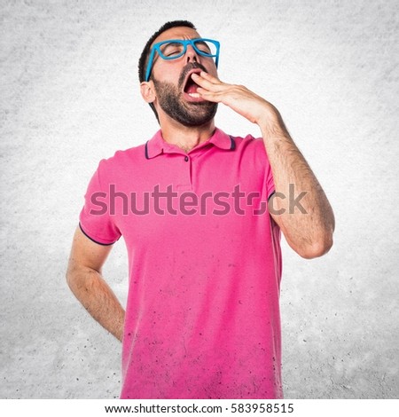 Man with colorful clothes yawning on grey textured background