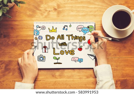 Do All Things with Love text with a person holding a pen on a wooden desk
