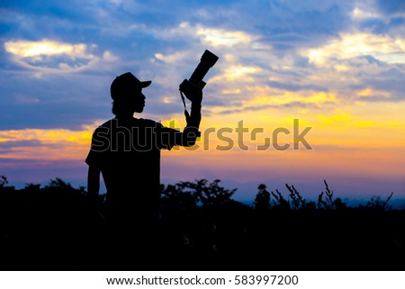 Silhouette of a photographer on sunset background.