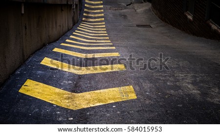 Yellow chevrons painted on road in urban alley way