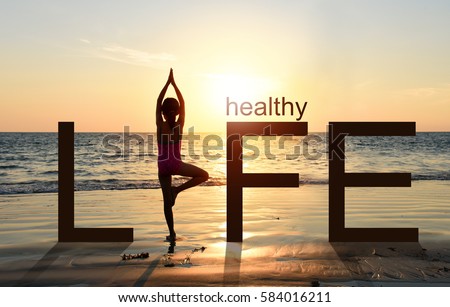  Silhouette of A girl practicing Yoga vrikshasana tree pose on tropical beach with sunset sky background, watching the sunset, standing as a part of the wording concept for healthy life. 