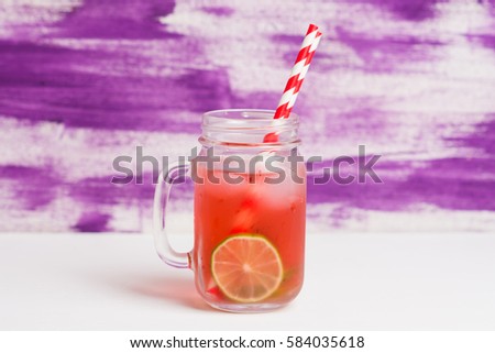 Raspberry lemonade with lice and ice in the glass on the wooden background