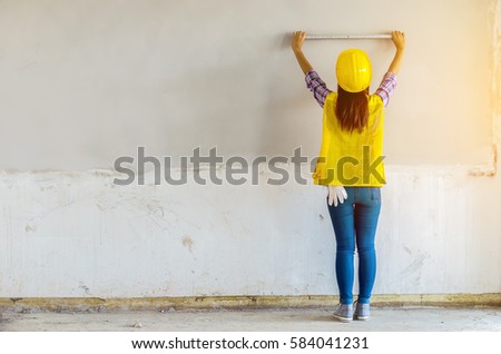 Young architect take a measurement on the wall at construction site