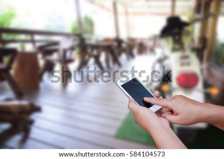 blurred photo and smartphone on woodden chair and table setting on a terrace