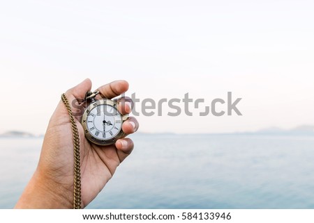 vintage golden pocket watch in hand, blurred sea as background